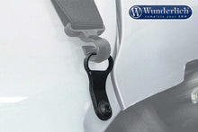 Black strapping loop attached to a vehicle, made of anodised aluminium, suitable for securing luggage.